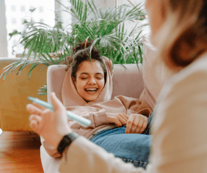 A teenage girl lies on a couch in a therapist's office and laughs