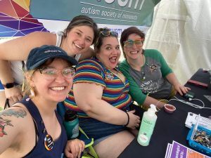 Four AuSM staff members pose at a resource table, really hamming it up