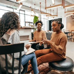 A group of women sits at a cafe, chatting together