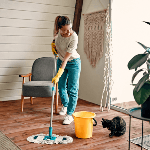 A woman cleans her floor with a bucket and a mop
