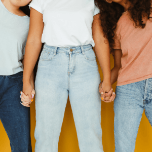 Three people stand hand in hand against a plain backdrop