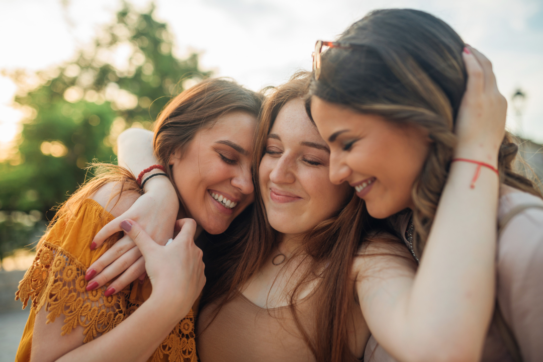 Three women hug each other with big smiles on their faces