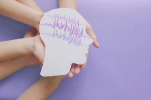 Hands hold a cut out of a head with squiggly lines inside of it