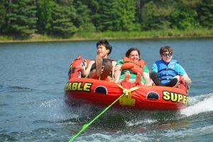 3 people riding a huge inner tube on a lake
