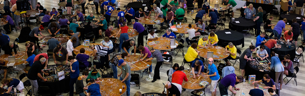 An overhead shot of many tables with people doing puzzles