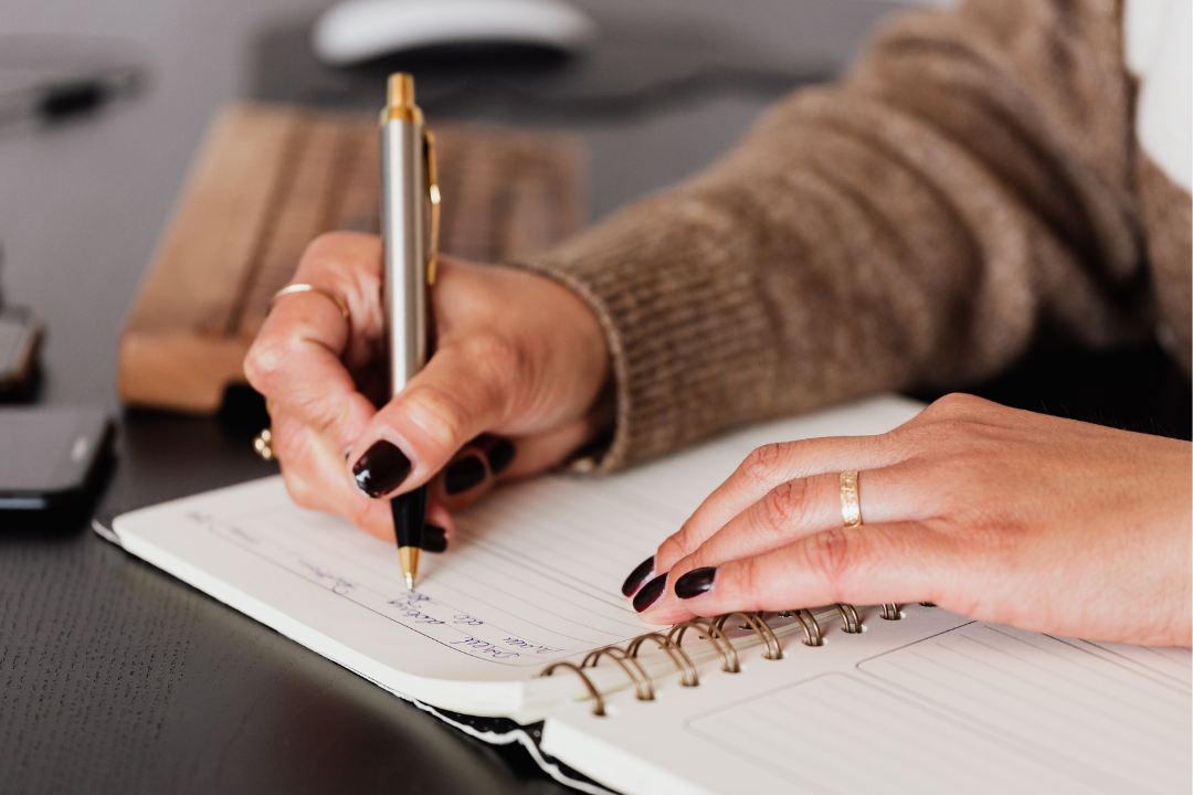 A closeup of a woman's hands writing in a planner