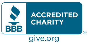 "BBB Accredited Charity seal in blue with white text. The seal features the BBB torch icon on the left and the words 'ACCREDITED CHARITY' to the right. Below, it includes the website 'give.org' in blue."