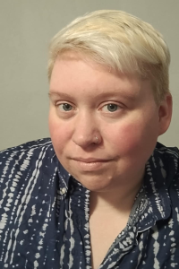 A man with short blonde hair wearing a button down