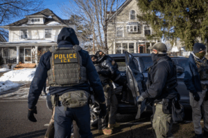 A woman is surrounded by masked federal agents and shoved into an unmarked vehicle.