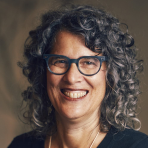 Emily Goldberg, a white woman with curly gray hair, wearing glasses and smiling.